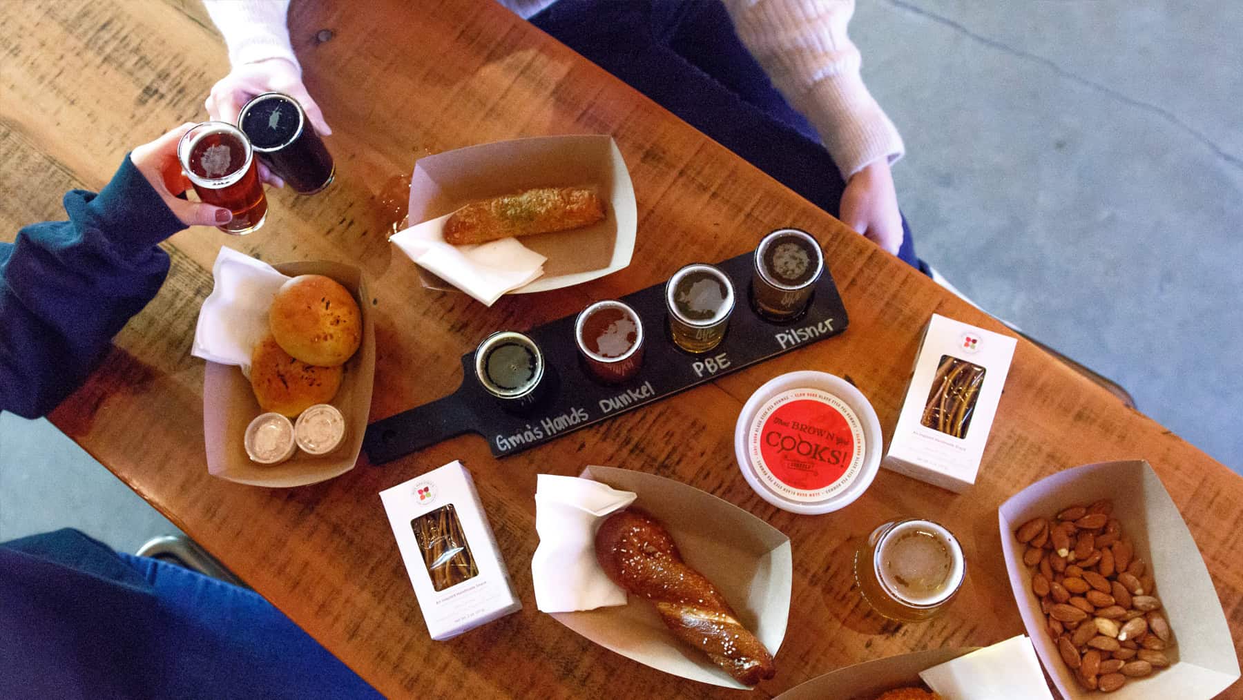 A table full of food and a flight of Grandma's Hands, Dunkel, PBE, and Pilsner beer.