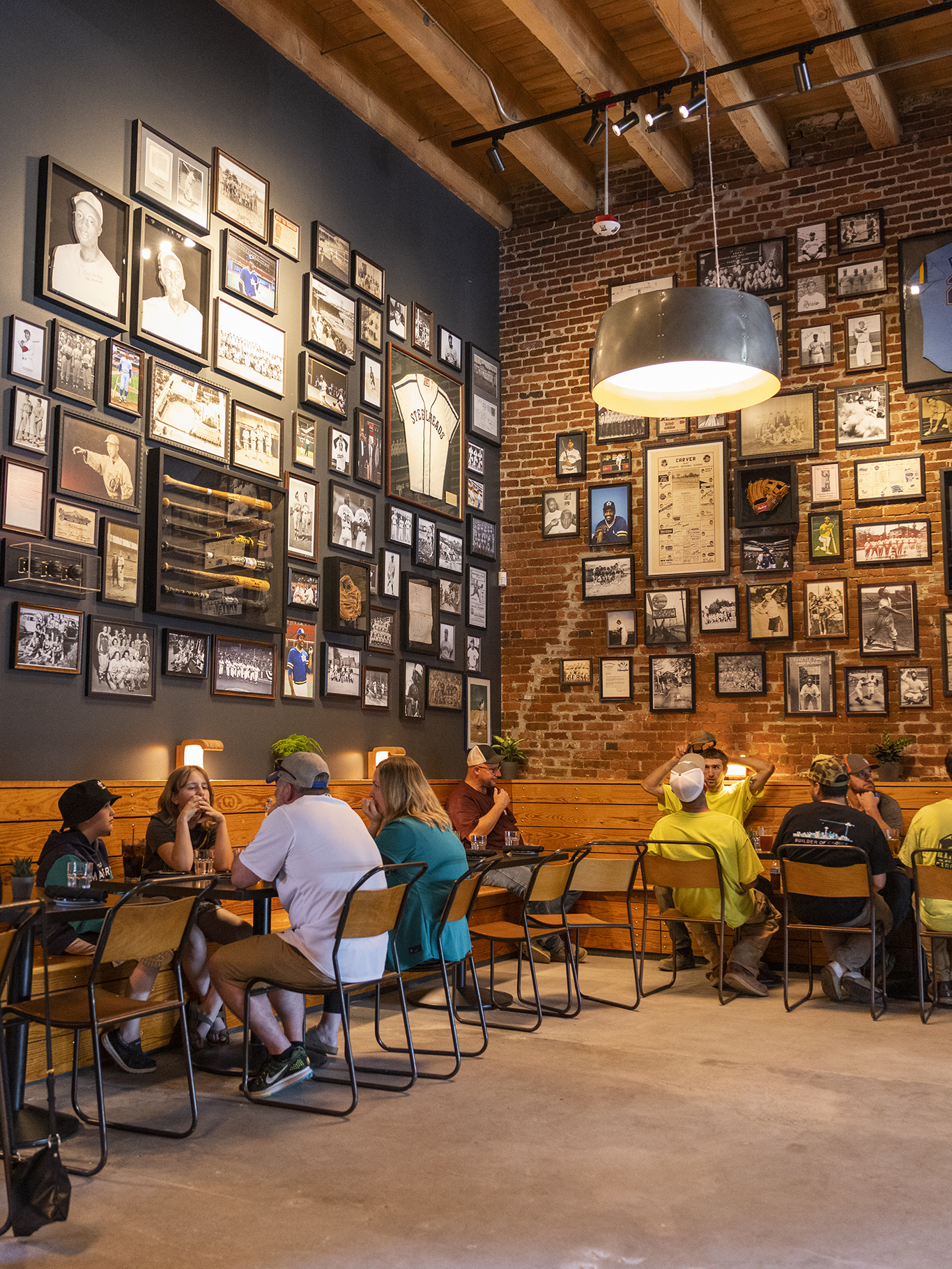 A corner of the Steelheads Alley bar with tables full of customers and both walls fully decorated with baseball decor.