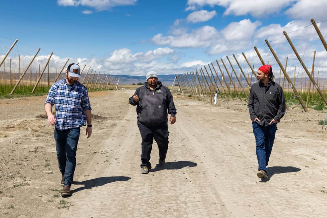 Three people walking toward the camera on a dirt road.