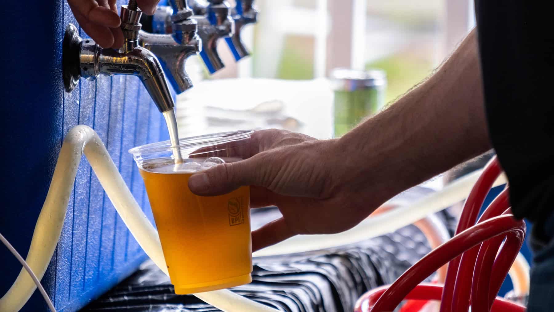 A plastic cup being filled at a beer tap.