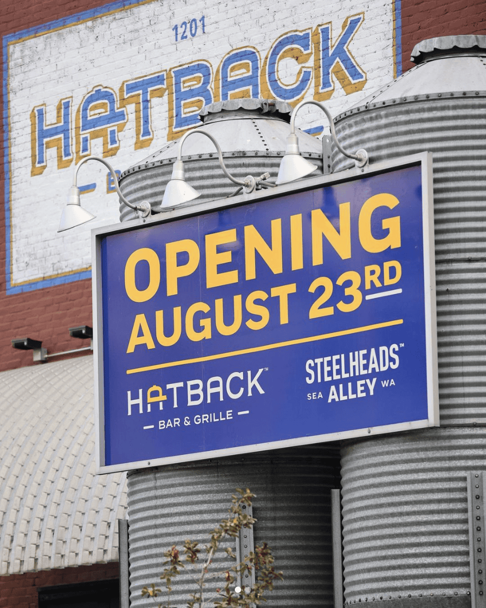 An ad board that says 'Opening August 23rd, Hatback Bar & Grille, Steelheads Sea Alley WA'