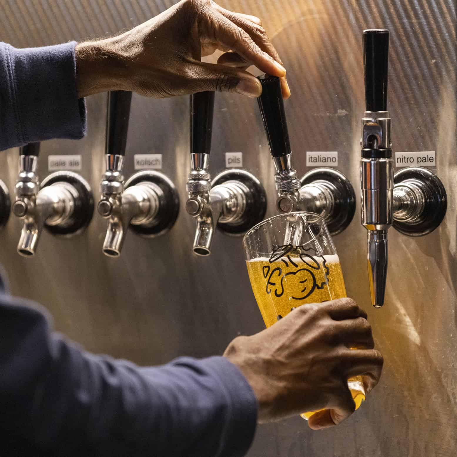 Row of beer taps showing beer being poured